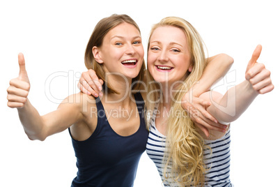 Two young happy women showing thumb up sign