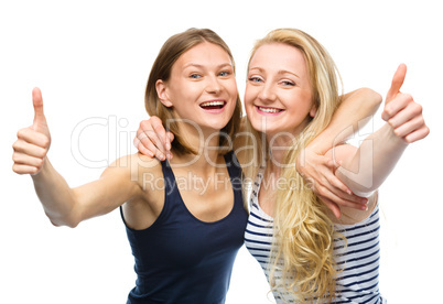 Two young happy women showing thumb up sign