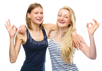 Two young happy women showing OK sign