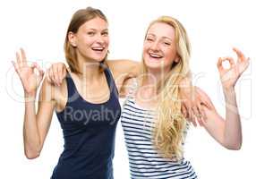 Two young happy women showing OK sign