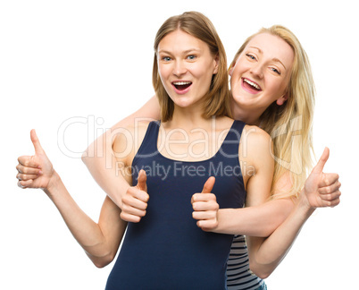 Two young happy women showing thumb up sign