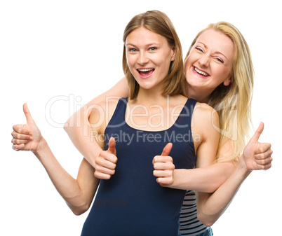 Two young happy women showing thumb up sign