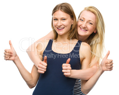 Two young happy women showing thumb up sign