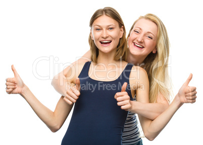 Two young happy women showing thumb up sign