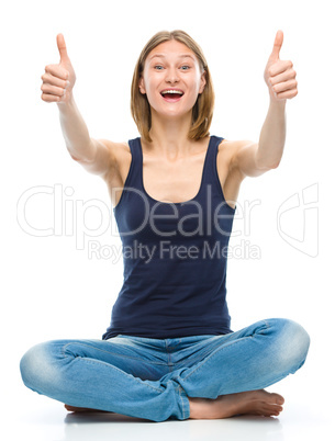 Young happy woman is showing thumb up sign