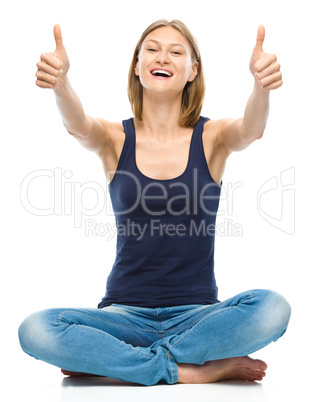 Young happy woman is showing thumb up sign