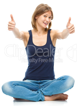 Young happy woman is showing thumb up sign