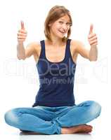 Young happy woman is showing thumb up sign