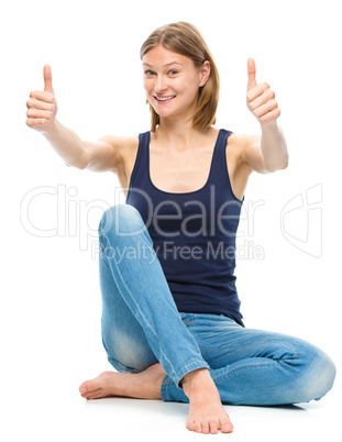 Young happy woman is showing thumb up sign