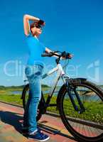 Young woman is standing in front of her bicycle