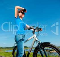 Young woman is standing in front of her bicycle