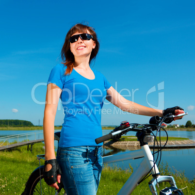 Young woman is standing in front of her bicycle