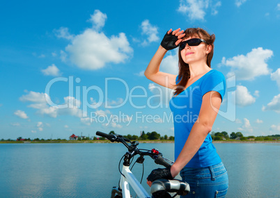 Young woman is standing behind of her bicycle