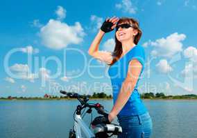 Young woman is standing behind of her bicycle