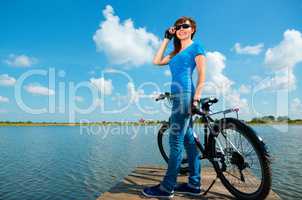 Young woman is standing in front of her bicycle