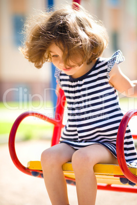 Young happy girl is swinging in playground