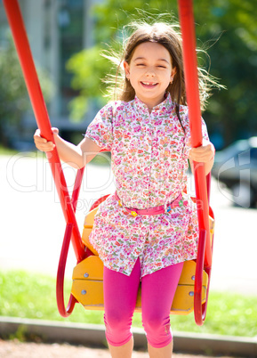 Young happy girl is swinging in playground