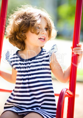 Young happy girl is swinging in playground