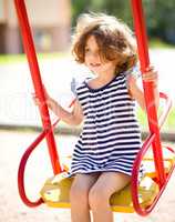 Young happy girl is swinging in playground