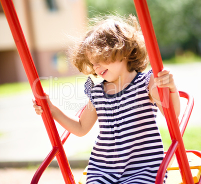 Young happy girl is swinging in playground