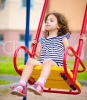 Young girl is swinging in playground
