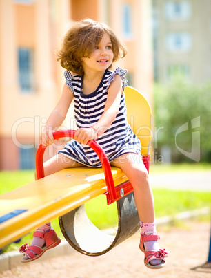 Young happy girl is swinging in playground