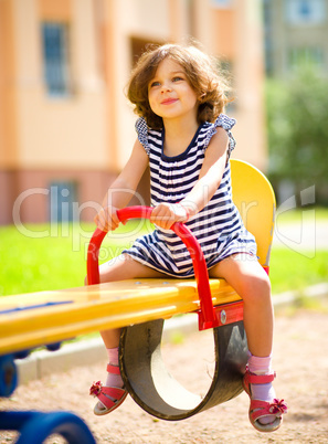 Young happy girl is swinging in playground