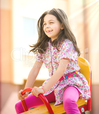 Young happy girl is swinging in playground