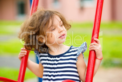 Young happy girl is swinging in playground