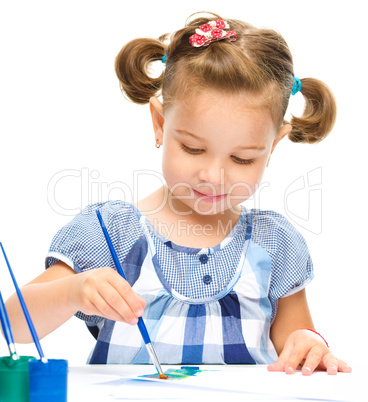 Little girl is painting with gouache