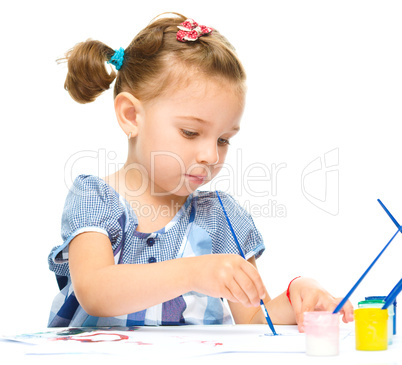 Little girl is painting with gouache