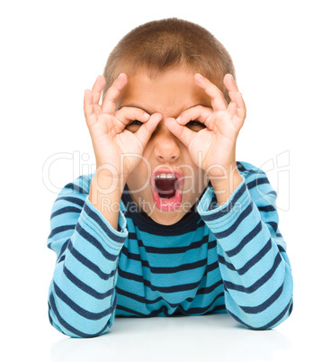 Astonished little boy is showing glasses gesture