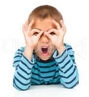 Astonished little boy is showing glasses gesture