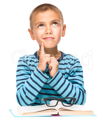 Young boy is daydreaming while reading book