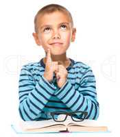 Young boy is daydreaming while reading book