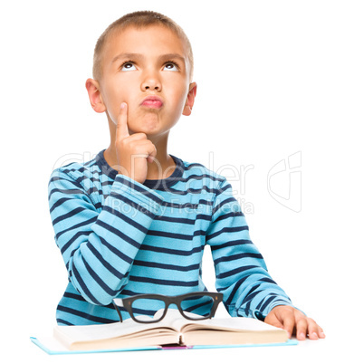 Young boy is daydreaming while reading book