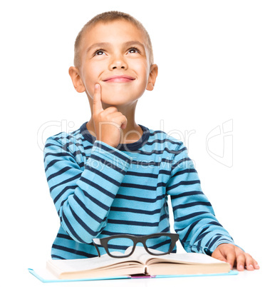 Young boy is daydreaming while reading book