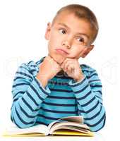 Young boy is daydreaming while reading book