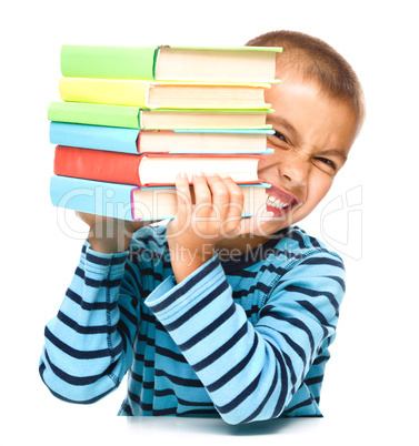 Little boy is holding a pile of books