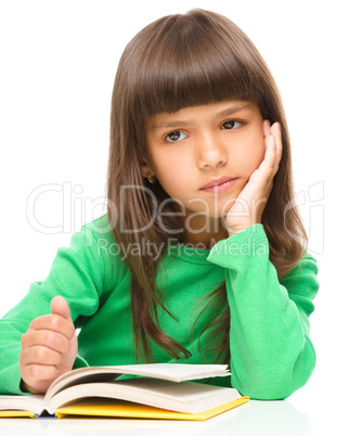 Young girl is daydreaming while reading book