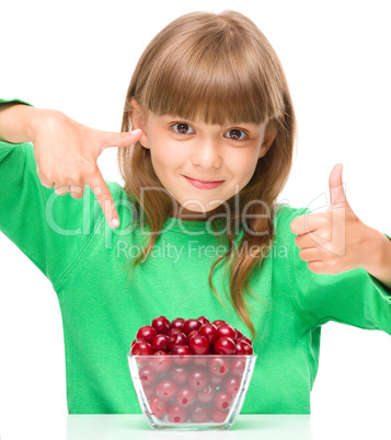 Cute girl is eating cherries showing thumb up sigh