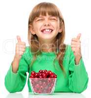 Cute girl is eating cherries showing thumb up sigh