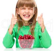 Cute girl is eating cherries showing thumb up sigh