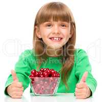 Cute girl is eating cherries showing thumb up sigh