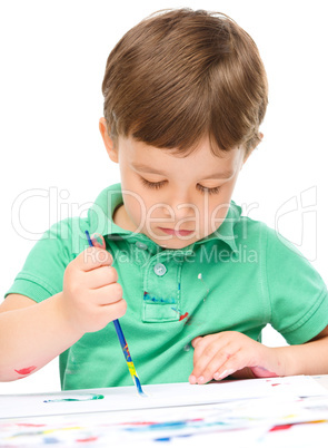 Little boy is playing with paints