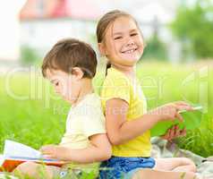 Little girl and boy are reading books outdoors