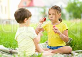 Little girl and boy are blowing soap bubbles