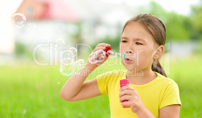 Little girl is blowing a soap bubbles