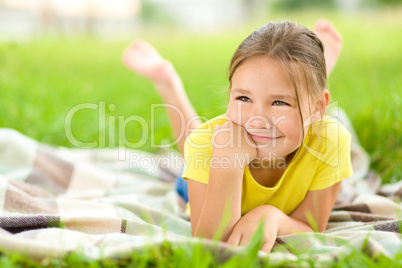 Portrait of a little girl laying on green grass