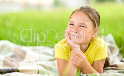 Portrait of a little girl laying on green grass